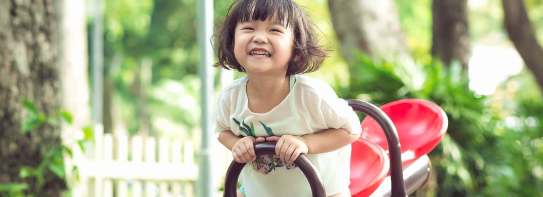 A smiling young Asian girl on a playground